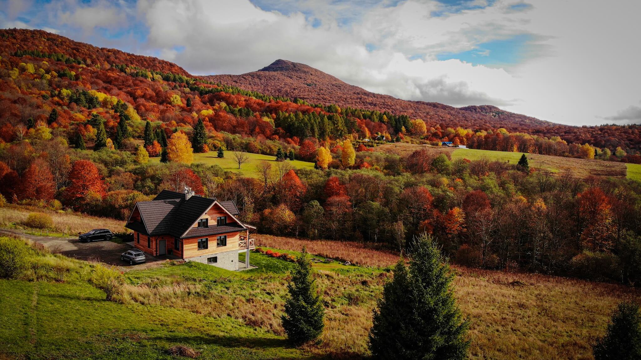 Blick auf ein Haus in Bukowe Tarasy, umgeben von herbstlichen Bäumen und Bergen.